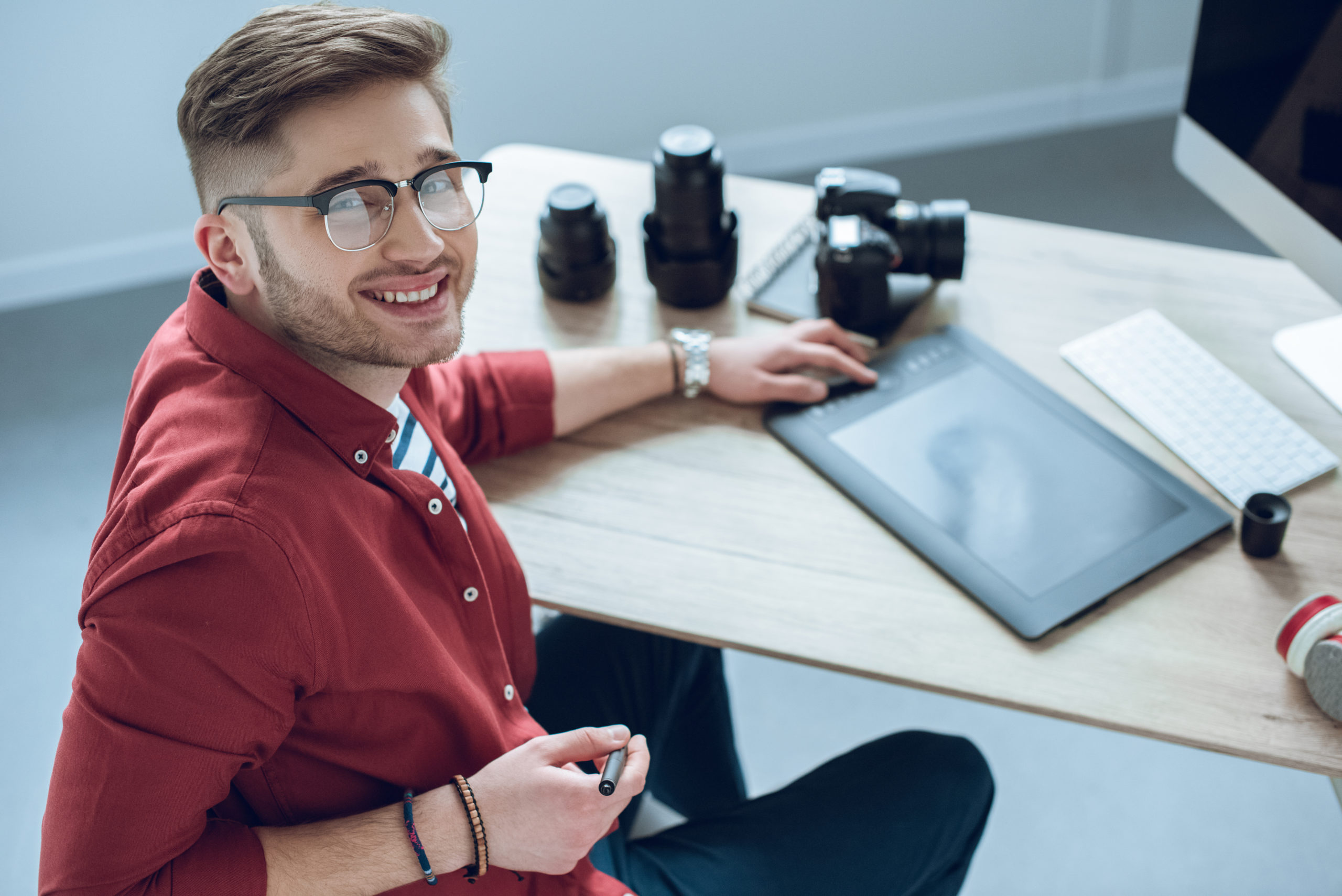 Happy freelancer man sitting by working table with graphic tablet